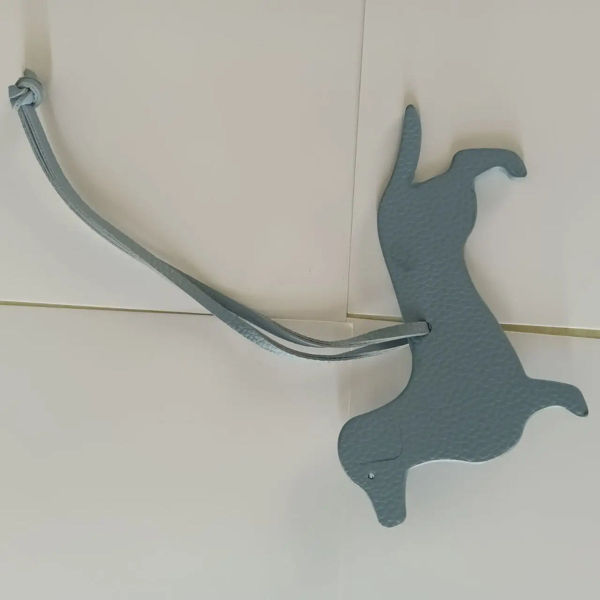 A gray PU leather keychain shaped like a dachshund and bulldog, attached to a loop.