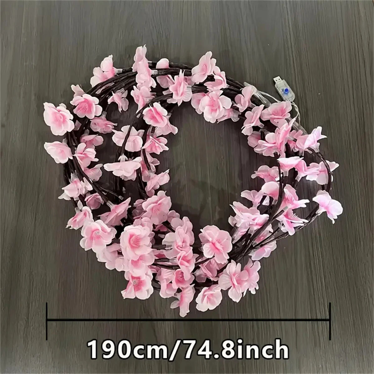 A circular wreath of pink cherry blossoms made from LED string lights with a USB power source.