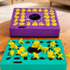 A purple timed board game and a teal board game with yellow puzzle pieces on a wooden surface.