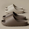A pair of taupe-colored EVA slides for men and women are shown in a stacked arrangement.