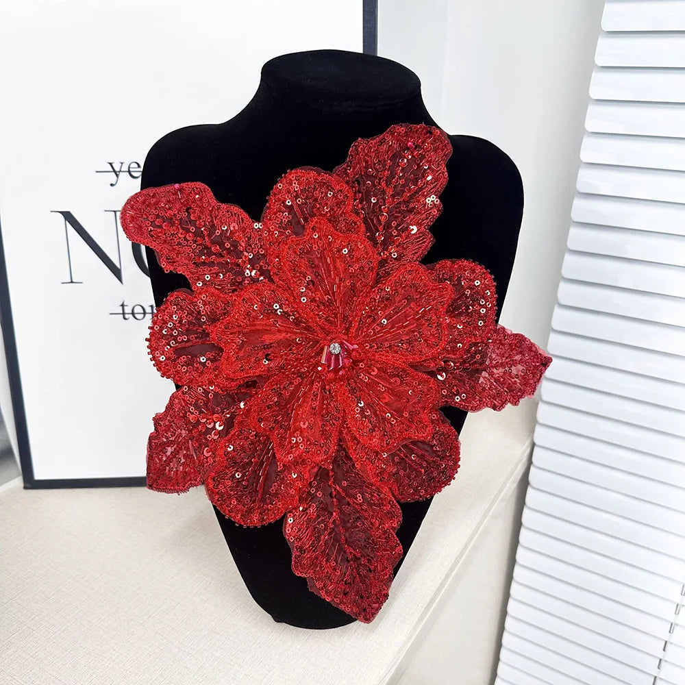 A vibrant red floral lace applique patch covered in sequins displayed on a black mannequin.