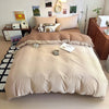 A beige ultra-soft washed cotton duvet cover set with four pillows and a matching duvet on a bed.