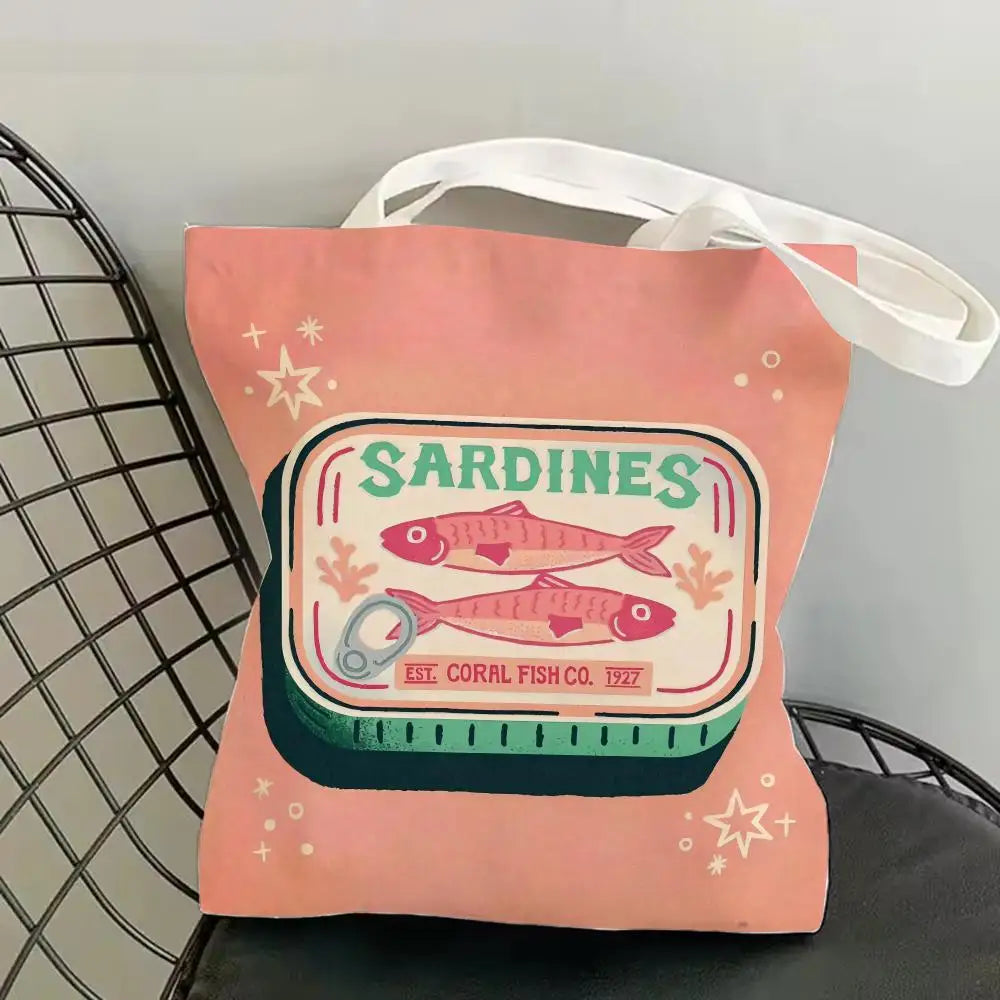 A pink canvas tote bag featuring a graphic print of sardines and text indicating Est. Coral Fish Co. 1927.