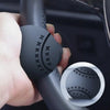 A hand is holding a black steering wheel knob with a textured grip pattern for one-hand control.