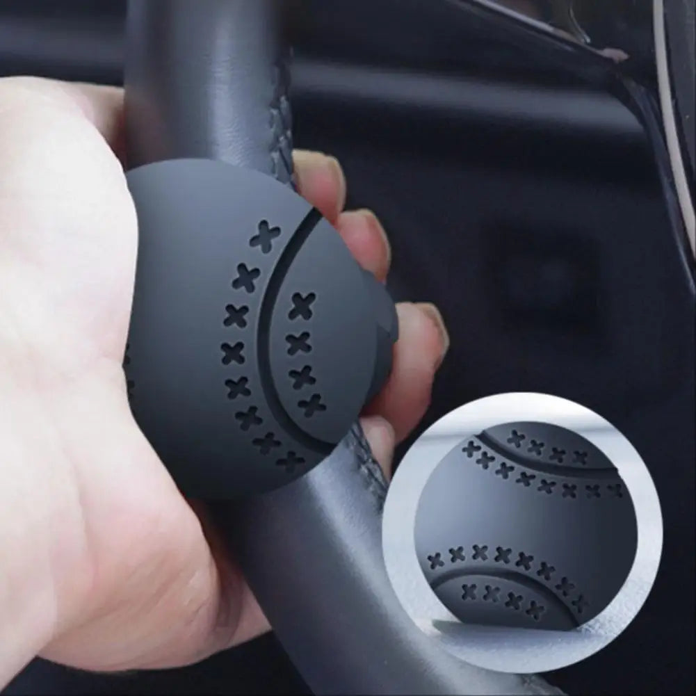A hand is holding a black steering wheel knob with a textured grip pattern for one-hand control.