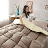A woman is posing with a luxury white goose and duck down comforter on a bed.