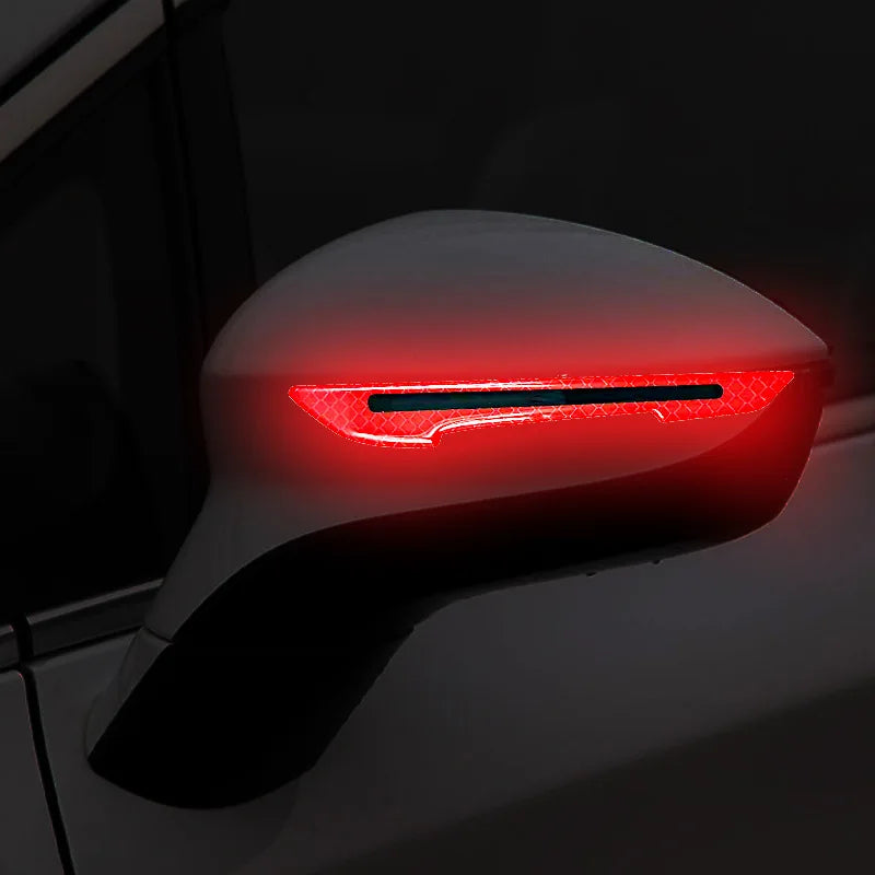 Close-up of a car mirror with bright red reflective safety strips illuminated.