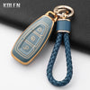 A silicone car key fob cover in a light blue-green color with gold accents attached to a leather strap.