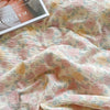 A soft pink and yellow floral washed cotton gauze summer quilt draped on a surface.