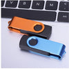 A close-up of two portable USB 2.0 flash drives in orange and blue colors resting on a laptop keyboard.