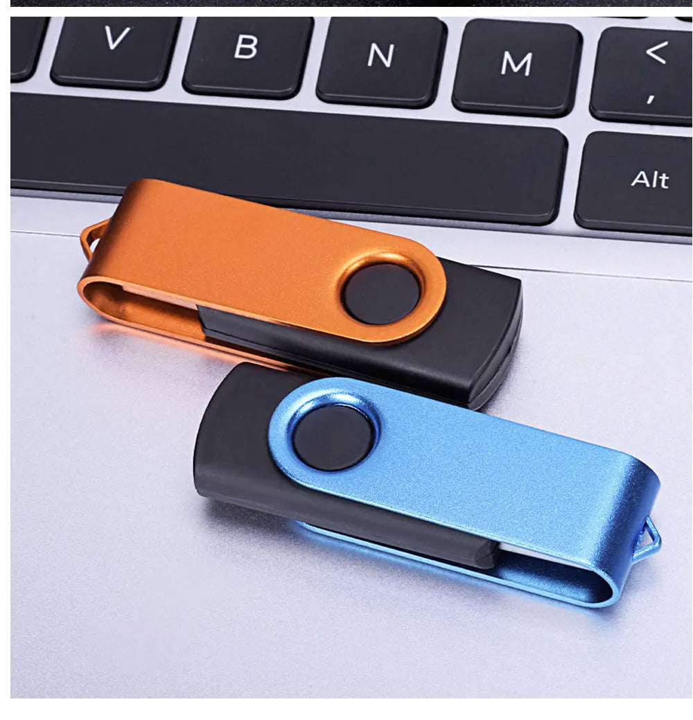 A close-up of two portable USB 2.0 flash drives in orange and blue colors resting on a laptop keyboard.