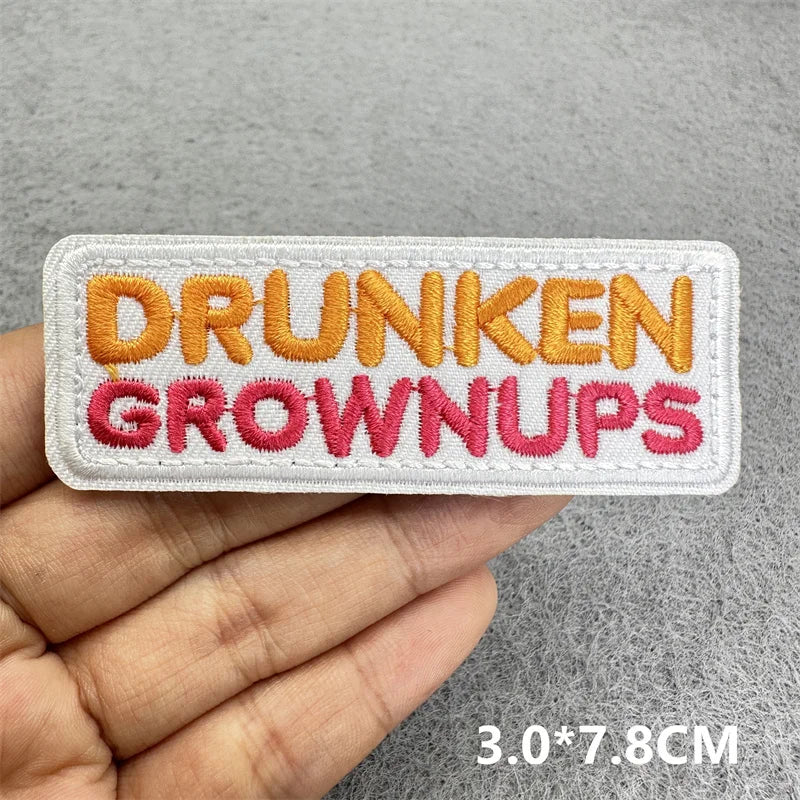 Embroidered patch with the text DRUNKEN GROWNUPS in orange and pink thread