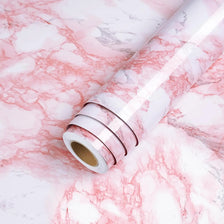 Roll of glossy pink marble contact paper lying on a white marble surface