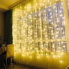 A window decorated with vertical strands of warm white fairy lights creating a glowing curtain effect.