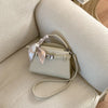 Elegante beigefarbene PU-Leder-Clutch mit geflochtenem Riem auf cremefarbener Polsterung.