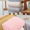 Stack of pink, blue, and beige plush velvet bath towels on a wooden surface.