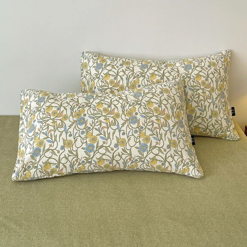 A set of soft printed bedding featuring a light background with yellow and blue floral patterns on pillows.