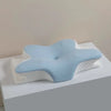 Light blue ergonomic memory foam cervical pillow resting on a white surface.