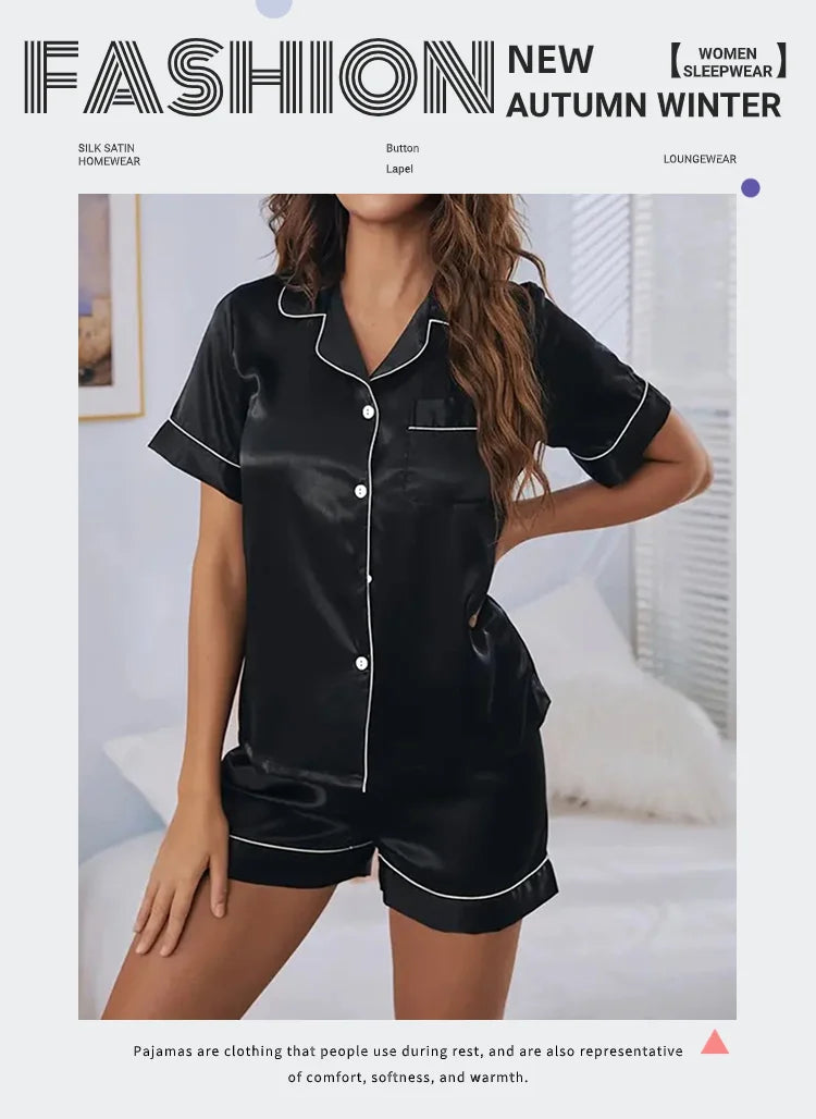 A woman models a black satin pajama set consisting of a button-down top and matching shorts.