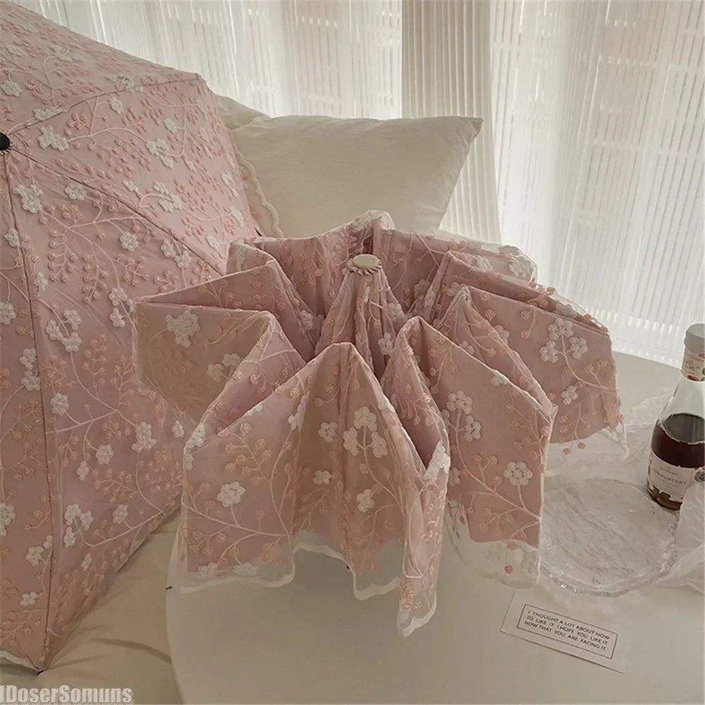 Pink lace double-layer folding umbrella shown folded on a white surface.