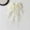 A white lace bow hair clip accessory with a delicate floral pattern.