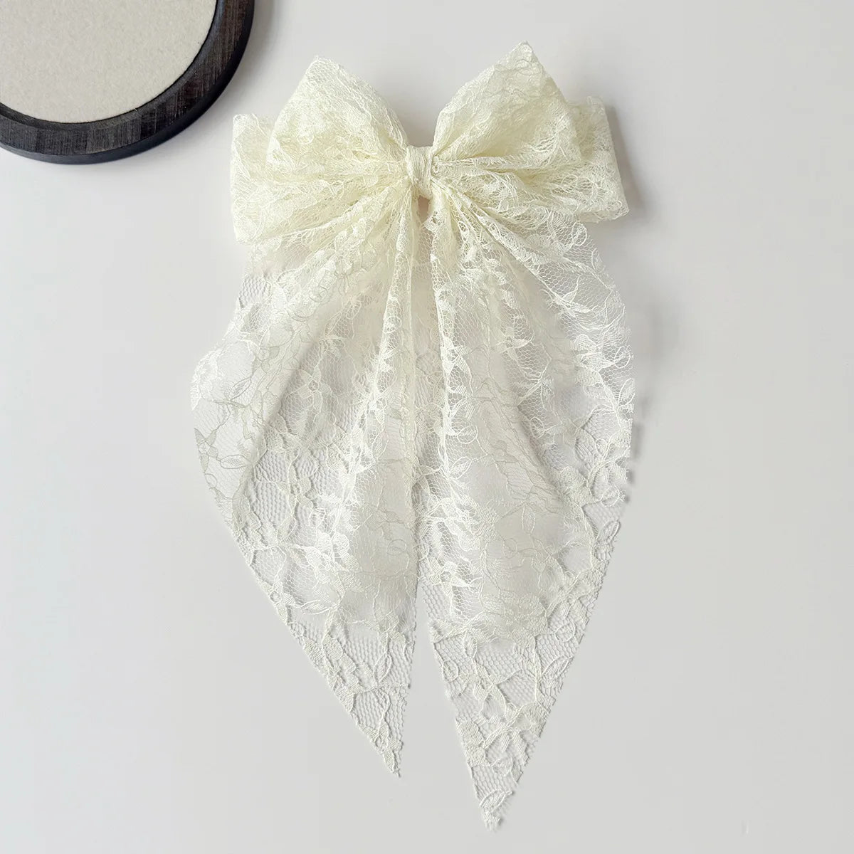 A white lace bow hair clip accessory with a delicate floral pattern.
