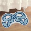 A light blue and white bow-shaped absorbent non-slip doormat placed on a wooden floor.