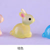 A set of three cute resin miniature bunny figurines in pink, yellow, and blue.
