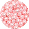 A close-up view of small, round pink imitation pearl beads for jewelry making.
