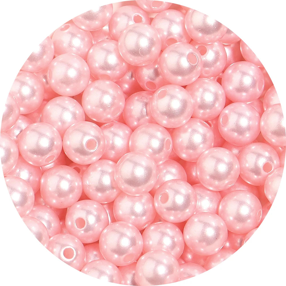A close-up view of small, round pink imitation pearl beads for jewelry making.