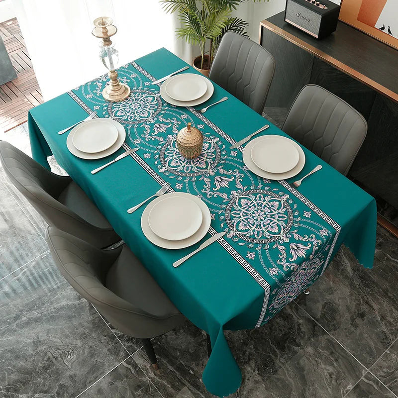 A teal tablecloth set for a dining table featuring white plates and silverware with a geometric blue and white pattern.