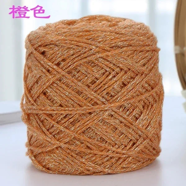 A ball of metallic silk crochet yarn in a coppery gold color used for knitting and macrame.