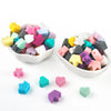 A collection of colorful silicone crown star heart beads in various shades are displayed in a white bowl and scattered on a w