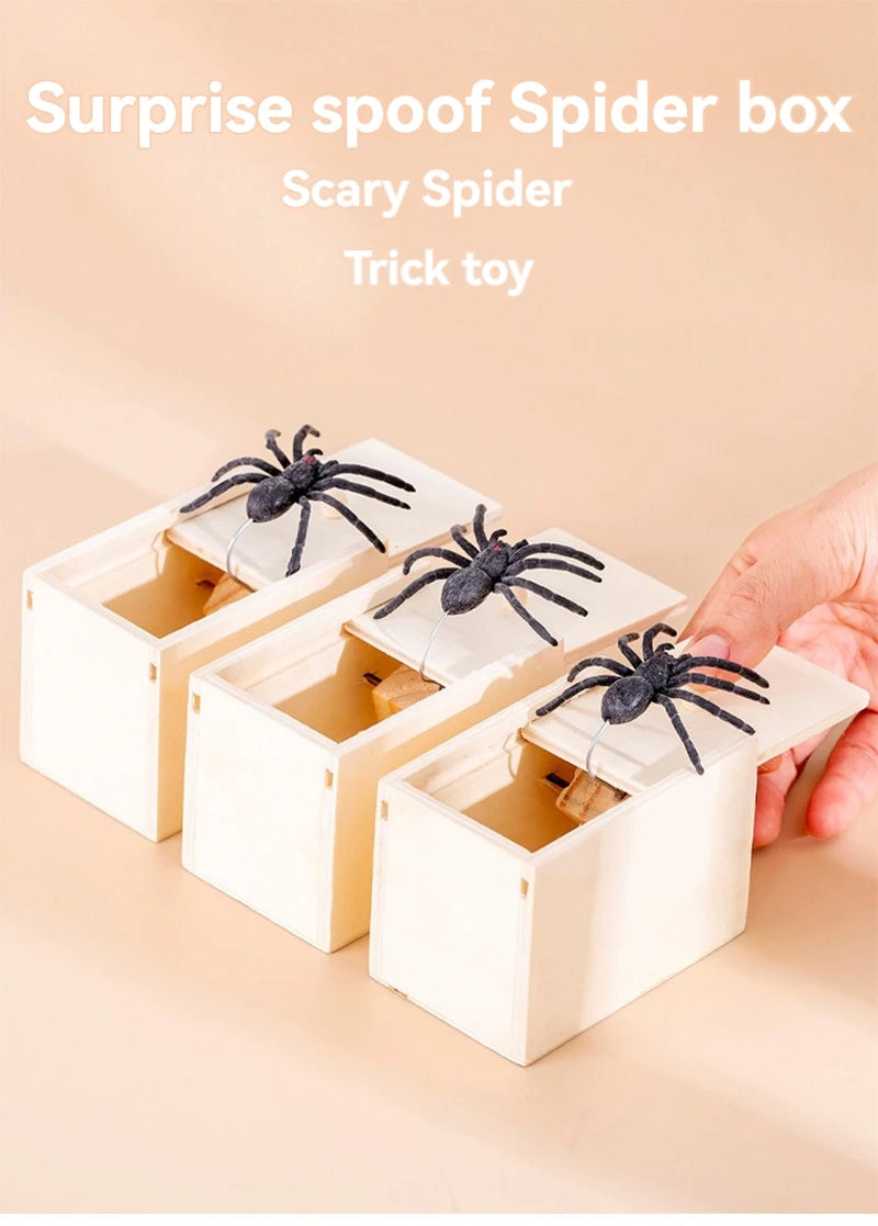 A hand holds an open wooden box containing a scary spider trick toy
