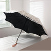 A black lace double-layer folding umbrella with a white patterned canopy is shown open on a white surface.
