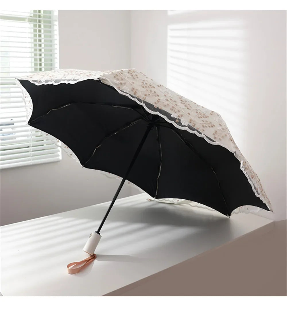 A black lace double-layer folding umbrella with a white patterned canopy is shown open on a white surface.