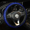 A close-up view of a black steering wheel covered in blue crystal rhinestones.