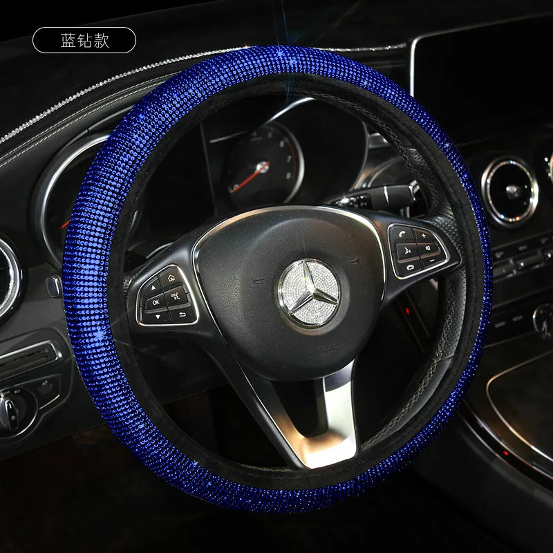 A close-up view of a black steering wheel covered in blue crystal rhinestones.