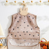 A beige waterproof baby feeding bib with a sleeveless design featuring small black and white hearts.