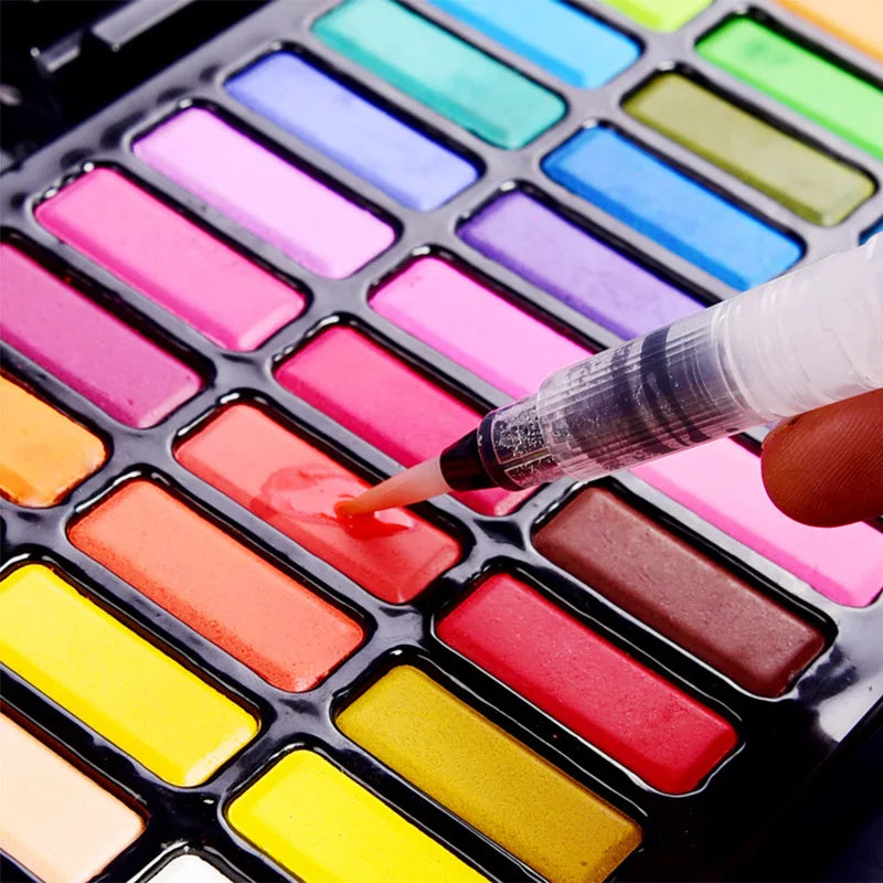 A hand applies pink watercolor paint onto a palette of various bright and pastel colors in a metal case.