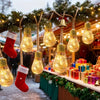 String lights decorated with pine branches and Christmas stockings hanging outdoors