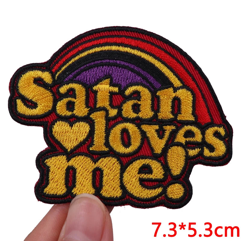 A black and red embroidered patch featuring the text Satan loves me in yellow and purple colors.