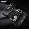 A black key fob cover with a carbon fiber style design is shown against a dark background.