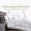A white goose down duvet is displayed on a bed, featuring quilted stitching and a gray headboard.