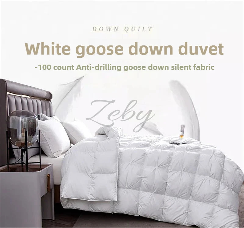 A white goose down duvet is displayed on a bed, featuring quilted stitching and a gray headboard.
