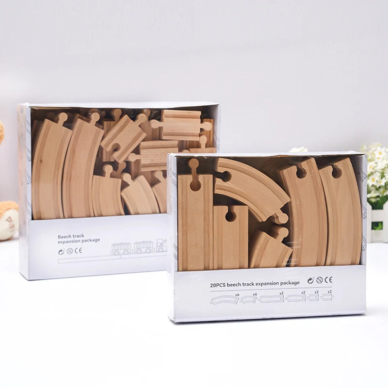 Two boxes of wooden train track expansion packs showing various curved and straight pieces for model trains.
