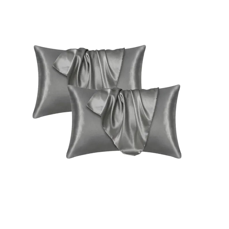 Un juego de tres fundas de almohada de satén gris suave y sedoso, dobladas y exhibidas.