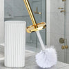 A white toilet brush set with a gold rotating handle and bristles resting on a marble surface.