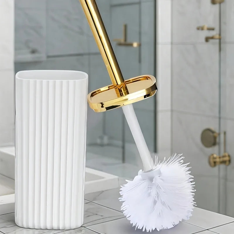 A white toilet brush set with a gold rotating handle and bristles resting on a marble surface.