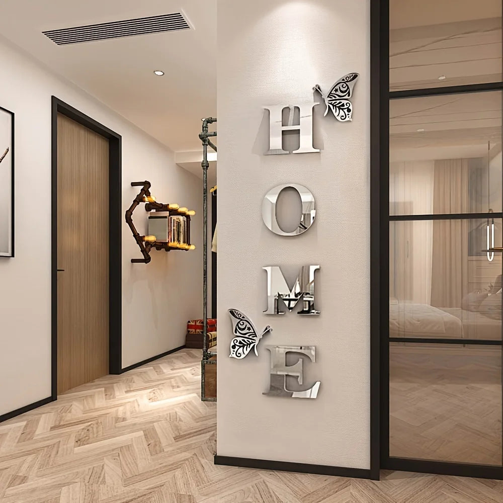 A display of six silver acrylic letter tiles H O M E on a white wall with a wooden door and light wood flooring.